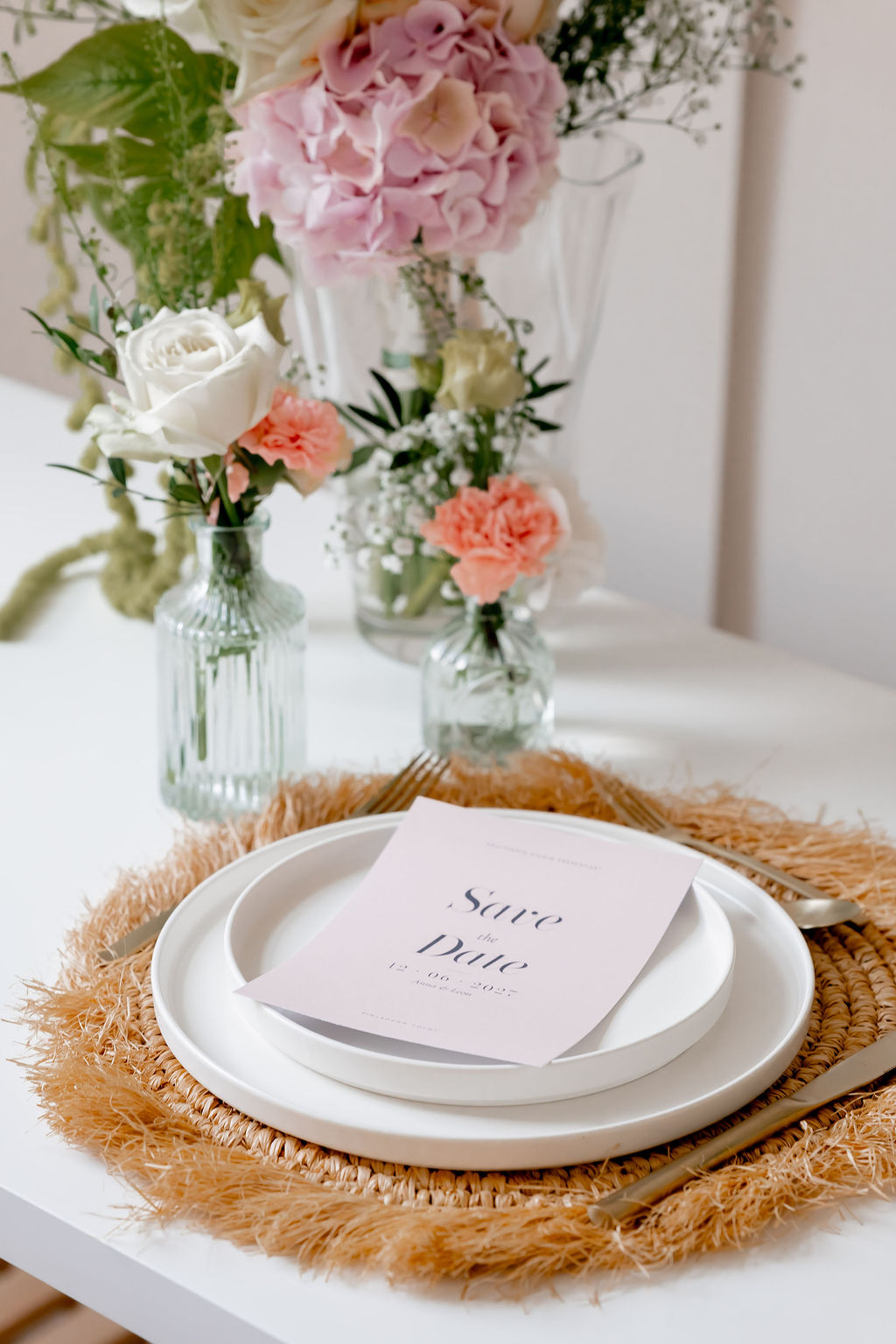 Gedeckter Hochzeitstisch mit Rattan-Platzset, Menükarte und Blumen in Rosé