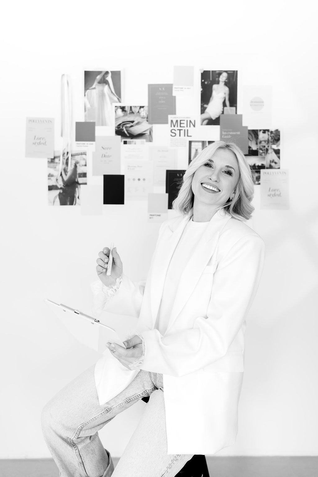 Hochzeitsplanerin Polly von Pollyvents Studio lachend vor ihrem Moodboard – Schwarz-Weiß-Porträt